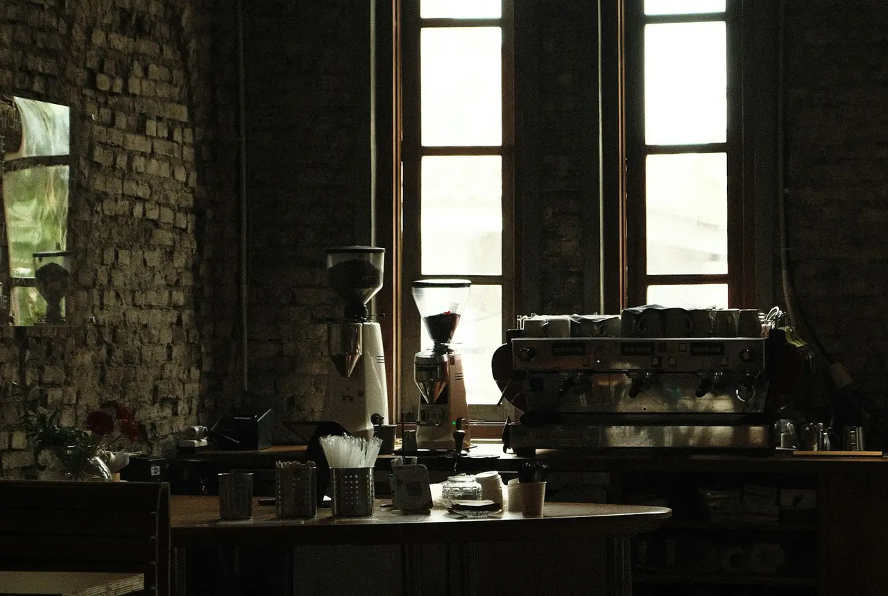 Interior de una cafetería con máquina de espresso junto a la ventana