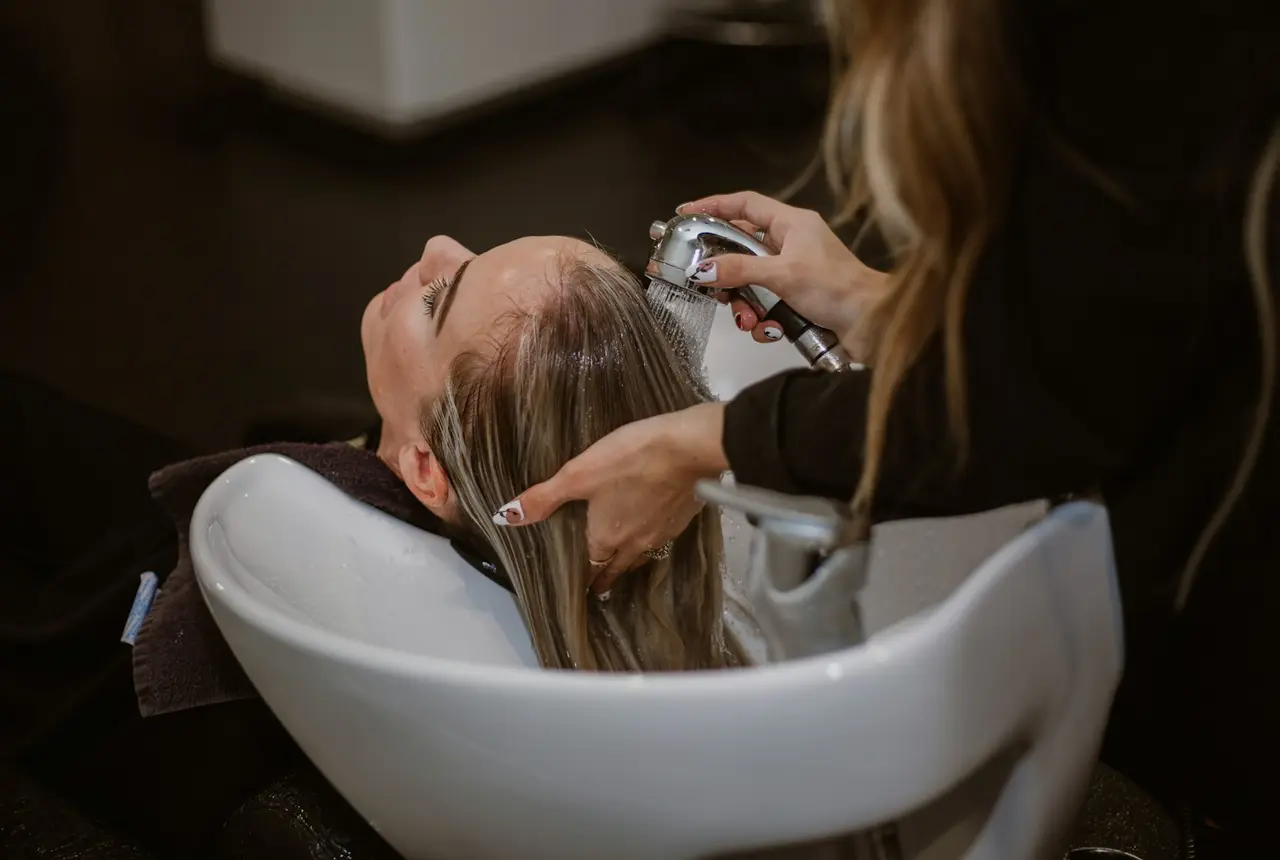 Estilista lavando el cabello de una clienta en un salón de belleza